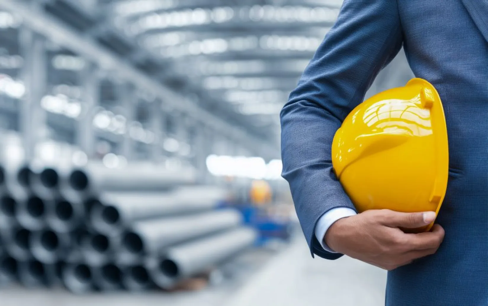 Hombre con traje con un casco de seguridad en su mano.