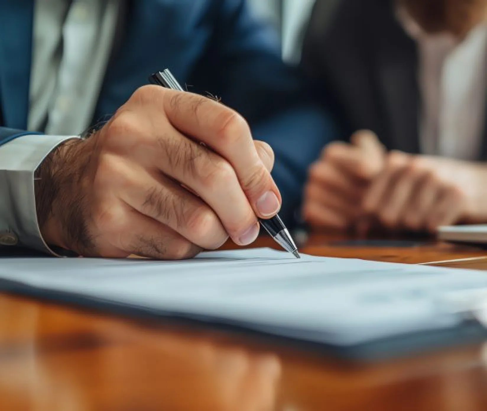 Manos de un hombre firmando un documento.