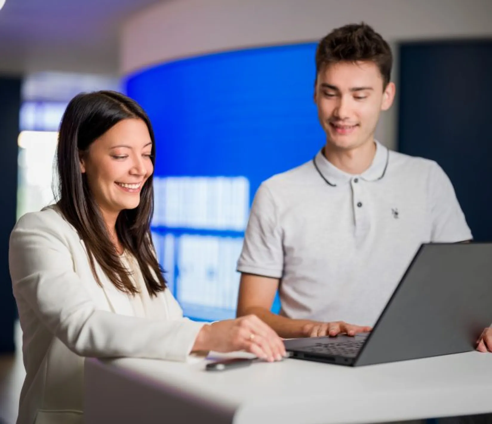 Chico y chica sonriendo frente a su ordenador. 